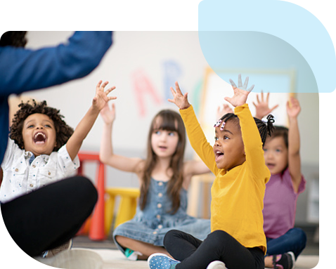 A group of kindergarten children enthusiastically raising their arms and shouting joy as they follow their teacher in a group activity.